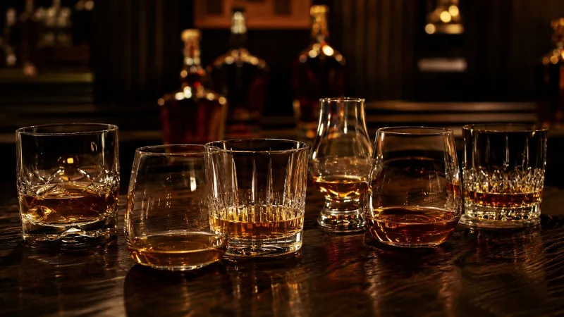 Muž si vychutnává sklenku whisky u stolu s dárkovou lahví - dárek pro muže